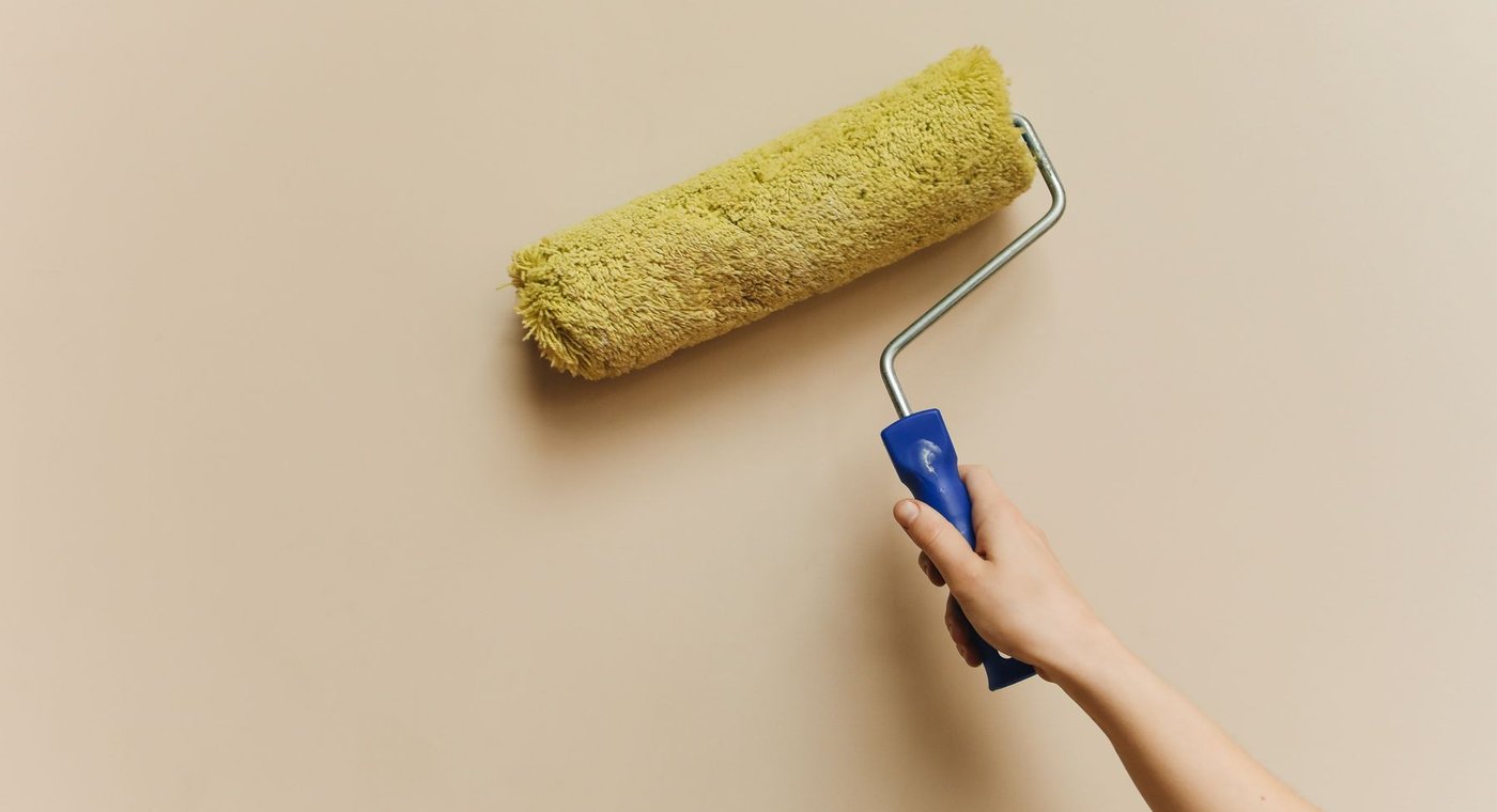 A paint roller rolling across a beige wall