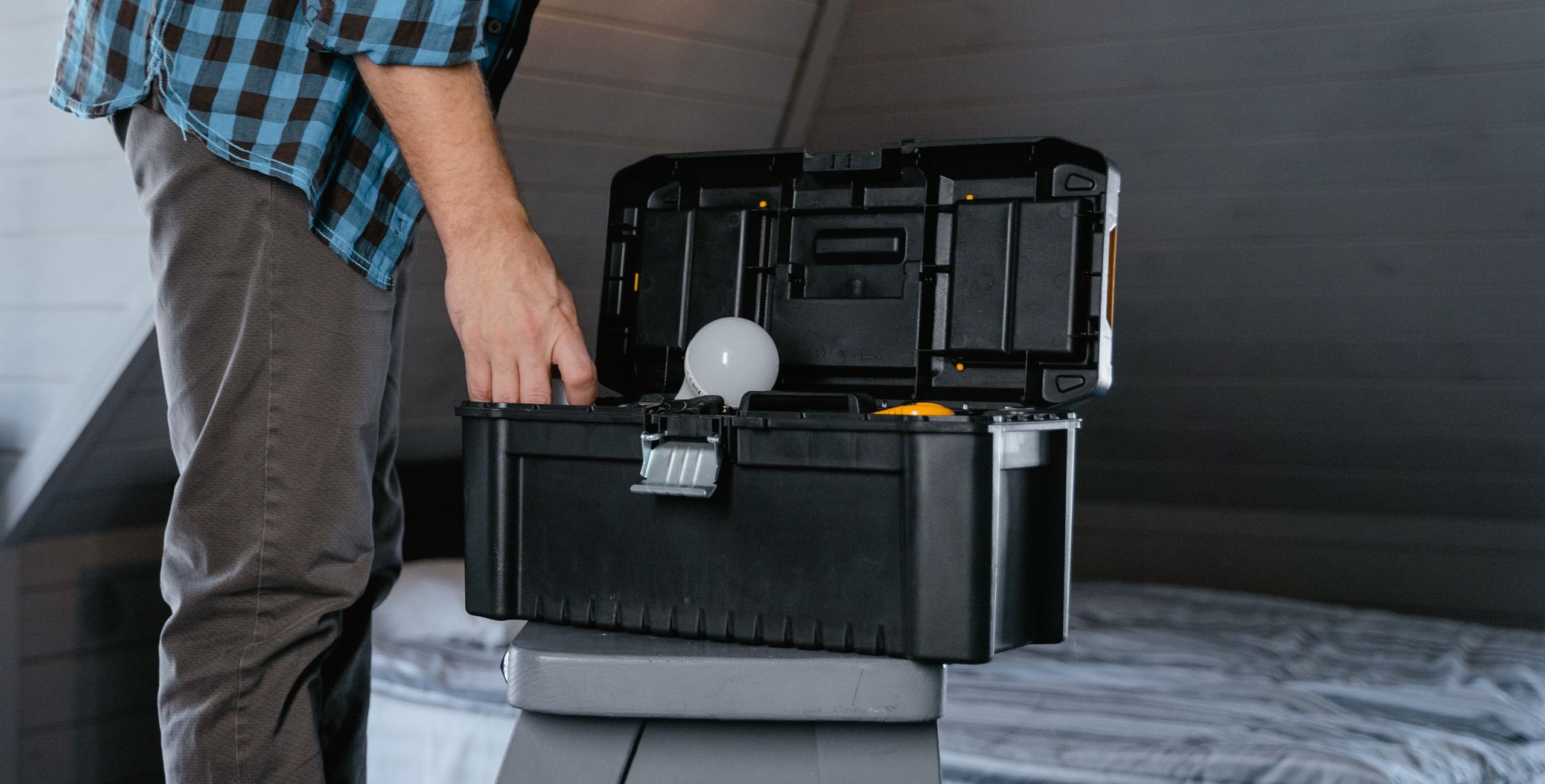 Handyman reaching into an open toolbox in a bedroom