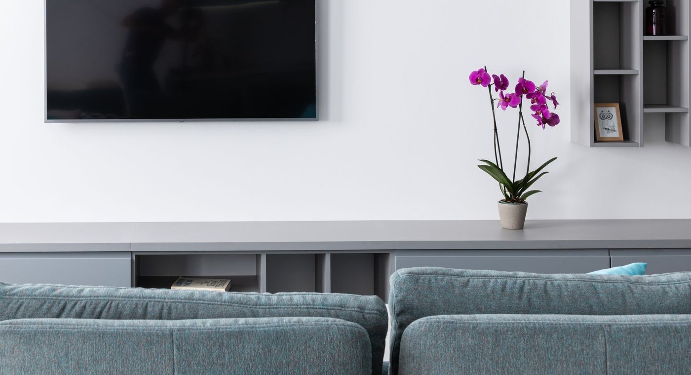 A wall-mounted TV and floating shelves above a gray sofa